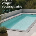 Piscine coque rectangulaire grise installée dans un jardin moderne